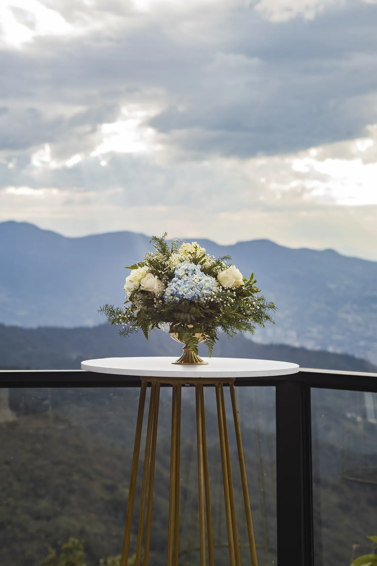 Mesa de cóctel con arreglo floral y vista a Medellín